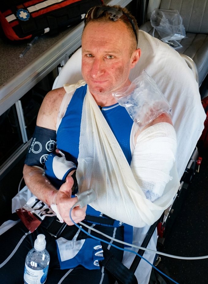 Peter Iccabazzi in an ambulance after a bike crash at St. George, arm in a sling, giving a thumbs up